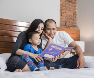a family gathers on a bed to read a story to a child