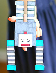 Paper robot balancing on a finger.