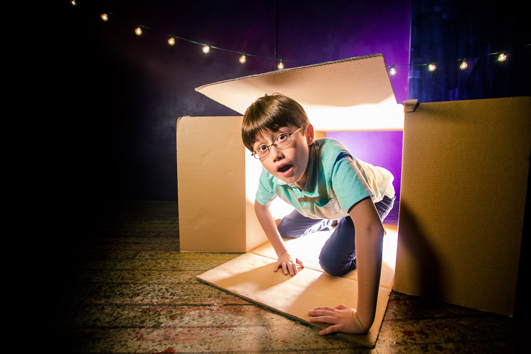A young boy playing pretend in a cardboard box
