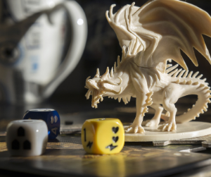 Some dice with a dragon figurine hulking in the background