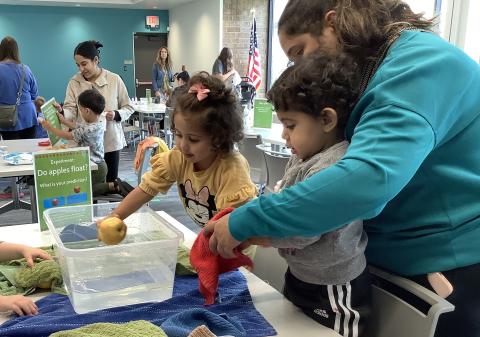 Parent working with two children at apple floating station.