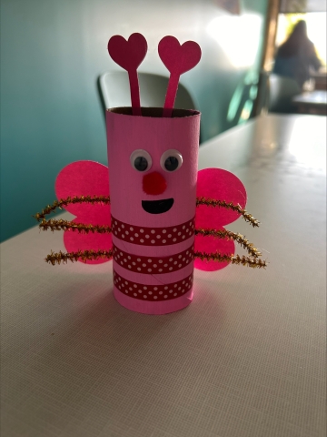 Pink cardboard roll decorated to look like a Valentines Day-themed bug.